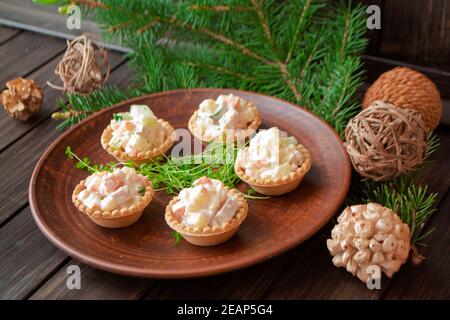 big brown plate, standing on the wooden table and served with a tartlets with olivier salad and piece for a restaurant banquet Stock Photo