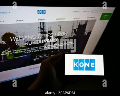 Person holding cellphone with logo of Finnish engineering and services company KONE Oyj in front of business webpage. Focus on phone display. Stock Photo