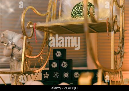 A golden Christmas sleigh in a festive setting with a calendar made of black numbered cubes Stock Photo