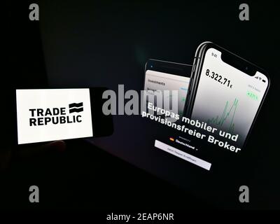 Person holding mobile phone with logo of German online broker Trade Republic Bank GmbH on screen in front of web page. Focus on cellphone display. Stock Photo