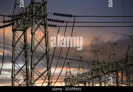 High voltage electric pylon and electrical wire against stormy sky and clouds. High voltage grid tower with wire cable. Transmission lines on high voltage grid tower. Three-phase electric power. Stock Photo