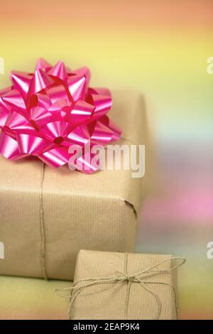 Two Gift boxes wrapped in plain brown paper with pink decoration and rainbow background, present for birthday or Valentine's day, mother's day background texture Stock Photo