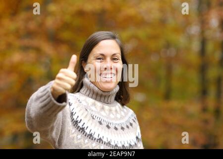 Happy adult woman gesturing thumbs up in autumn Stock Photo