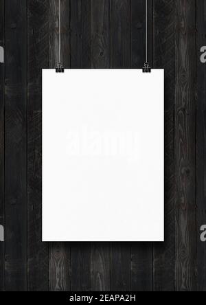 White poster hanging on a black wooden wall with clips Stock Photo