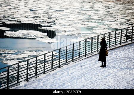 Berlin, Germany. 10th Feb, 2021. Germany, Berlin, February 10, 2021: A woman looks at floating ice sheets next to the Spree River. A weather phenomenon called the polar vortex split brought snow and icy winds to Berlin and Brandenburg with temperatures well below freezing. (Photo by Jan Scheunert/Sipa USA) Credit: Sipa USA/Alamy Live News Stock Photo