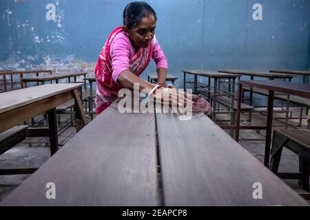 A staff member of Madhyamgram high school seen cleaning benches as the school prepares to reopen. The west Bengal government has decided to reopen schools across the state with proper covid 19 guidelines from 12th February. The schools will reopen for Classes 9 to 12 after ten months of being shut since March 16, 2020 due to the coronavirus pandemic. The state government has said that students will only be allowed to attend offline classes with parental consent. Stock Photo