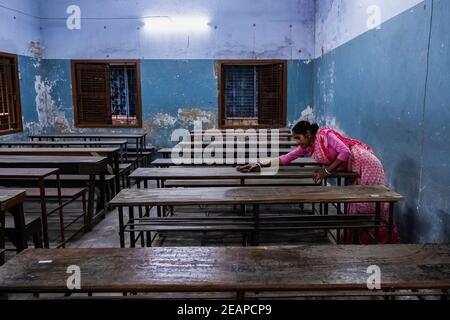 A staff member of Madhyamgram high school seen cleaning benches as the school prepares to reopen. The west Bengal government has decided to reopen schools across the state with proper covid 19 guidelines from 12th February. The schools will reopen for Classes 9 to 12 after ten months of being shut since March 16, 2020 due to the coronavirus pandemic. The state government has said that students will only be allowed to attend offline classes with parental consent. Stock Photo