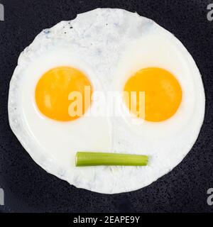 fried eggs with celery on black plate close up Stock Photo