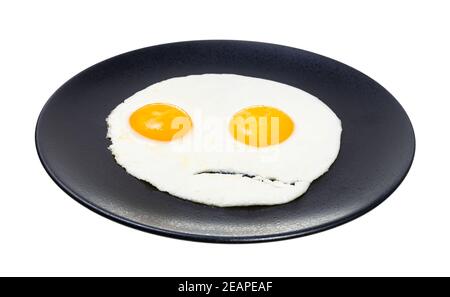 two fried eggs on black plate isolated on white Stock Photo