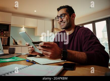 Smiling mixed race businessman holding digital tablet holding credit card making online purchase Stock Photo