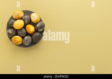 Golden and silver easter eggs in a plate isolated on yellow background