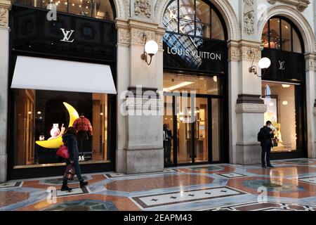 People with surgical masks in front of Louis Vuitton store in Galleria Vittorio Emanuele II in downtown Milan, Italy Stock Photo