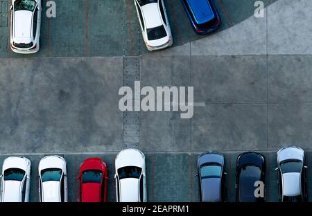 Top view concrete car parking lot. Aerial view of car parked at car parking area of apartment. Outdoor parking space with empty slot. One way traffic sign on road. Above view outside car parking lot. Stock Photo