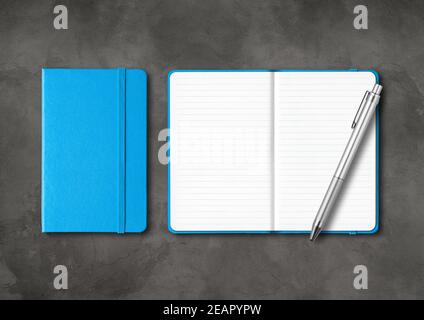Blue closed and open lined notebooks with a pen on dark concrete background Stock Photo