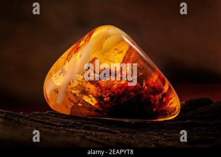 Beauty of natural raw amber. A piece of yellow-red transparent natural amber with inclusions in it. Stock Photo