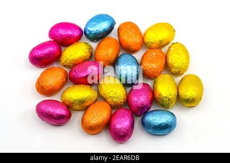 Small chocolate Easter eggs in coloured foil wrappings on a plain background. No people. Stock Photo