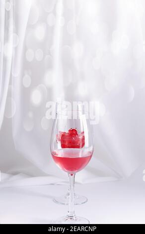 The concept of the background to Valentine's Day. Two glass glasses with remnants of wine on a white background, a vertical image with a copy of the s Stock Photo