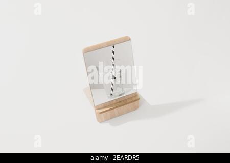 A glass of water with striped straw reflected in the mirror, isolated white backdrop. Abstract conceptual image of familiar house objects Stock Photo