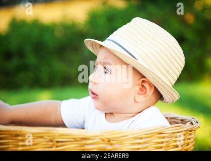 The little boy with a hat in a basket. Stock Photo
