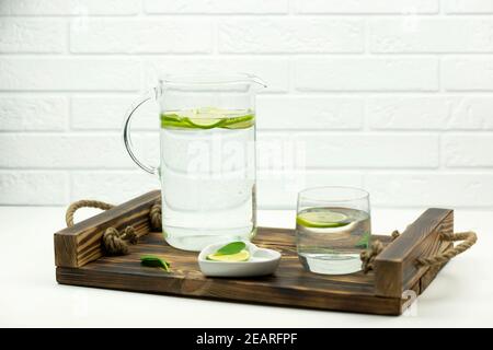 A home made lemonade made of lime stands in a glass and jug on a wooden tray Stock Photo