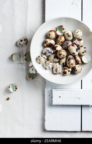 Quail eggs in a bowl on a white table, top view. Stock Photo