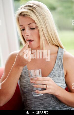 Woman taking tablet with glass of water Stock Photo