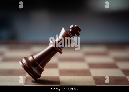 black chess king falling on chess board concept of failing. Stock Photo