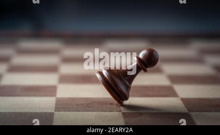 black chess pawn falling on chess board concept of failing. Stock Photo