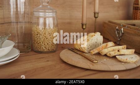 Sliced white bread on a wooden tray. Modern Scandinavian style kitchen. Pasta in a glass jar Stock Photo