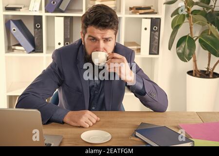 My energy. Office life routines. Respectable ceo. First coffee. Man handsome boss sit in office drinking coffee. Comfy workspace. Good morning. Bearded hipster formal suit relaxing with coffee. Stock Photo