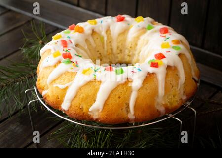 Candied berries bundt cake with lemon sugar glaze on wooden table. Homemade autumn and winter cozy holiday dessert on rustic table Stock Photo