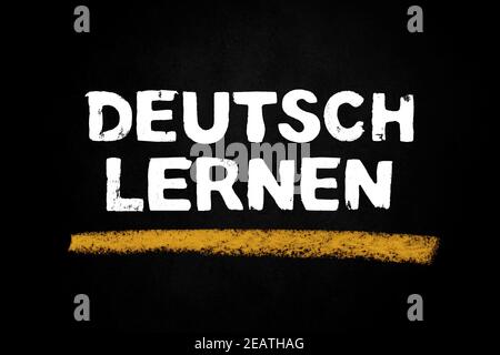 Black chalkboard showing: Learn german in german language Stock Photo