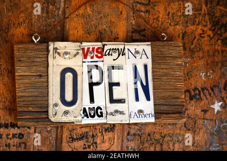 An Open sign made from recycled license plates on the front door of a general store, live music venue and bar in Luckenbach, Texas. Stock Photo