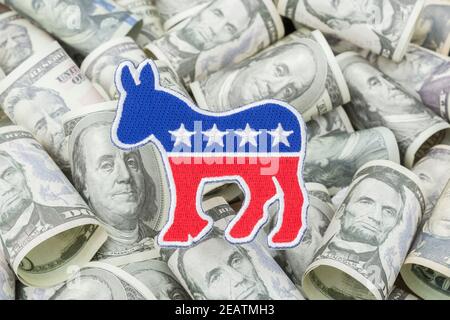 Democrat donkey logo patch badge & US dollar banknotes (training copies). For US political fundraising & Democrat PAC campaign funds, Biden debt pile. Stock Photo