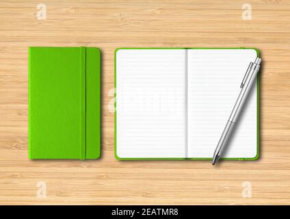 Green closed and open lined notebooks with a pen on wooden background Stock Photo
