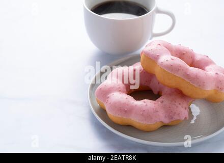 Hot coffee with pink donuts on a marble background Stock Photo
