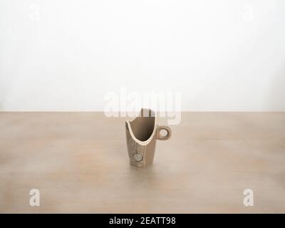 Broken in a cup on a white background. Fragments of the cup lying on the table Stock Photo