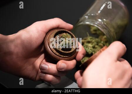 Cannabis in a grinder and other smoking utensils on a table Stock Photo