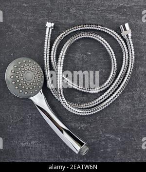 Top view, showerhead and flexible connection hose close-up on grey shabby background Stock Photo