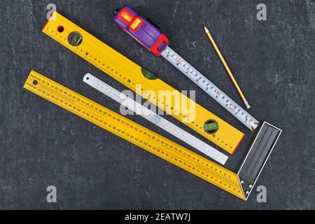 Ruler, tape measure, construction level and pencil on grey background, close-up view from above Stock Photo