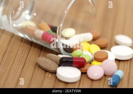Various drugs (tablets, pills, capsules) in small canted glass Stock Photo