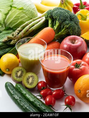 A lot of fruits and vegetables on a white background with a glass of green smoothie and vegetable juice Stock Photo