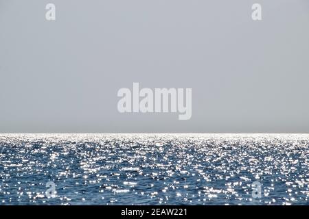 Sea line of the horizon. Sea and sky. The waves and glare of the sun are reflected from the waves of the sea. Seascape. Stock Photo