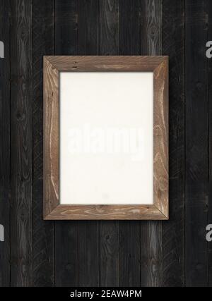 Old rustic wooden picture frame hanging on a black wall. Horizontal picture Stock Photo