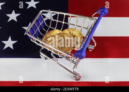 Three golden bitcoins in a supermarket cart, closeup, selective focus Stock Photo