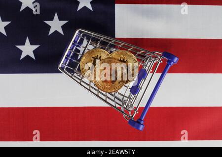 Three golden bitcoins in a supermarket cart, top view, selective focus Stock Photo