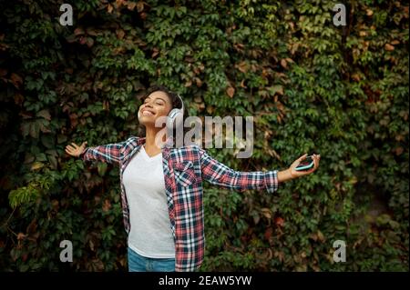 Woman in headphones listening to music in park Stock Photo