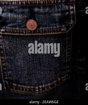 Selective focus on denim jean jacket pocket in clothes shop. Denim jacket pocket and button texture. Textile industry. Jeans fashion and shopping concept. Clothing concept. Denim jacket for sale. Stock Photo
