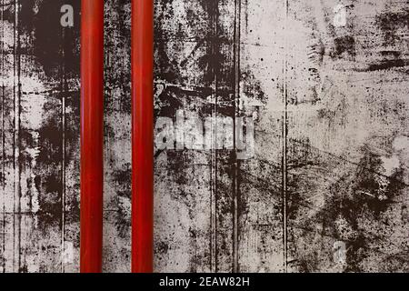 Part view of two red pipes on the black and white shabby painted concrete wall background Stock Photo