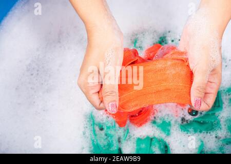 Woman use hands washing color clothes in basin Stock Photo